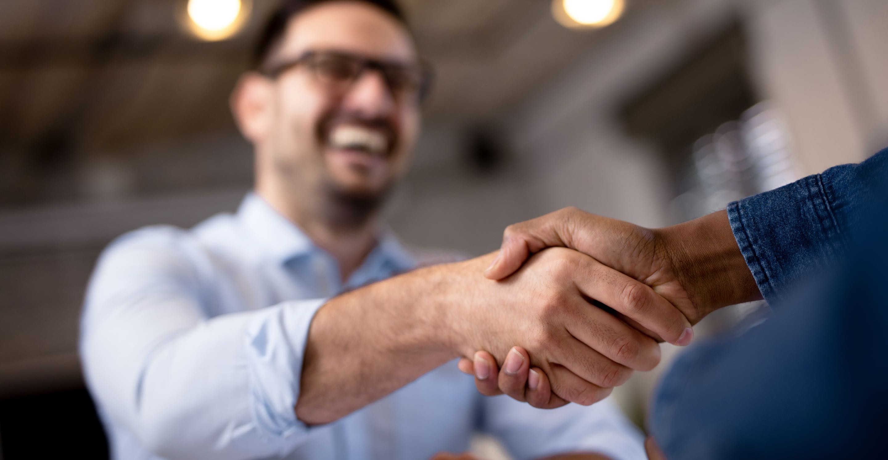 Two people shaking hands, one wearing a light blue shirt.